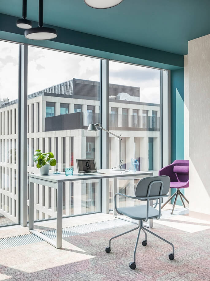 Bureau professionnel en verre et fauteuil de travail &agrave; roulettes devant une fa&ccedil;ade enti&egrave;rement vitr&eacute;e