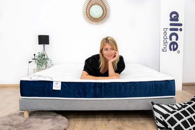 Femme allong&eacute;e sur un matelas &agrave; ressorts pour en &eacute;prouver le soutien