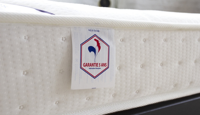 Gros plan sur le flanc capitonn&eacute; d'un matelas enfant et son &eacute;tiquette de garantie