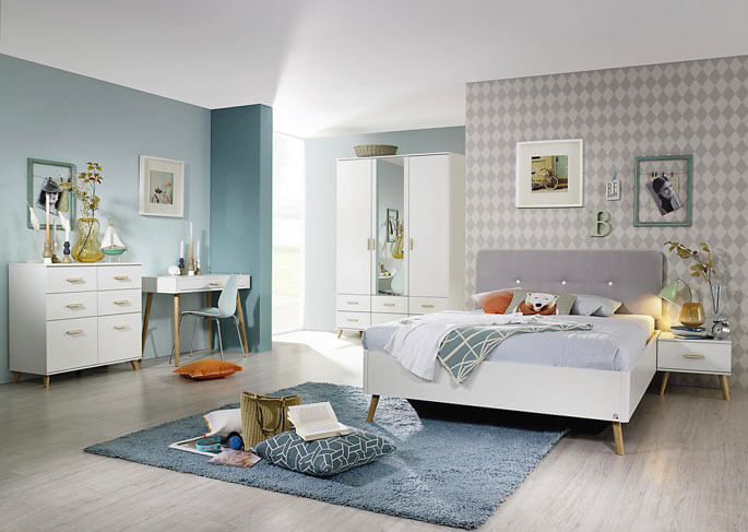 Chambre scandinave en blanc laqué, tête de lit capitonnée et tapis bleu sur parquet clair