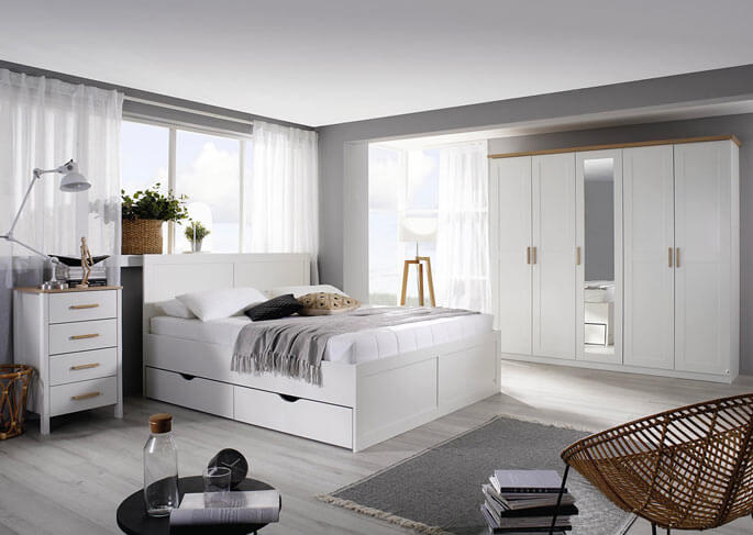 Chambre scandinave blanche avec armoire, lit double et fauteuil en rotin