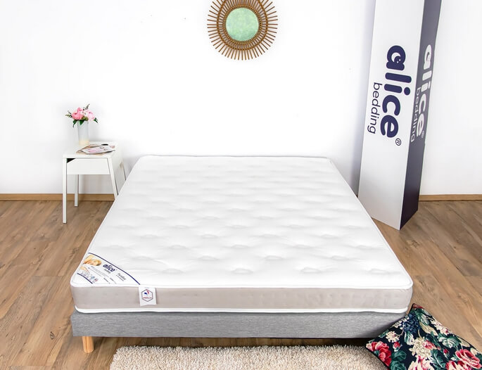 Matelas blanc capitonné posé sur un sommier bas