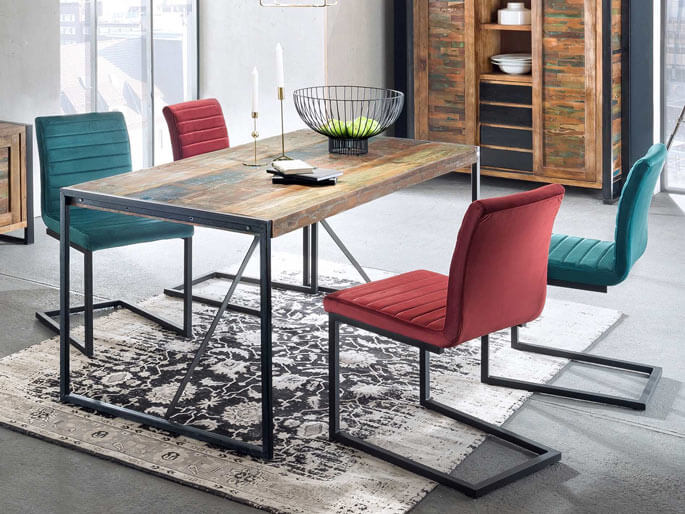 Table à manger en bois et métal noir entourée de chaises colorées